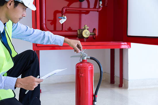 man inspecting a fire extinguisher