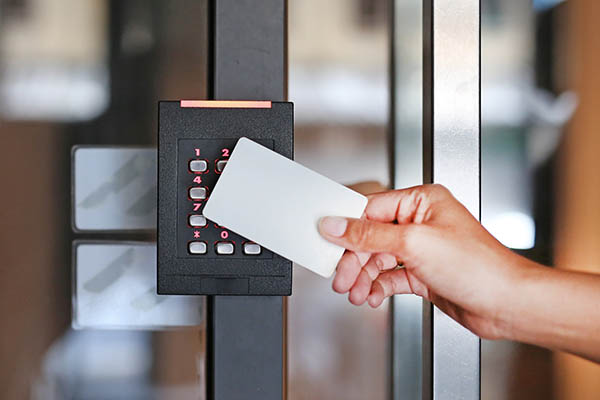 Hand using key card to open the door to a secured facility