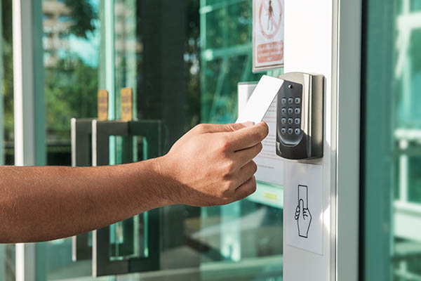 Hand using key card to open the door to a secured facility